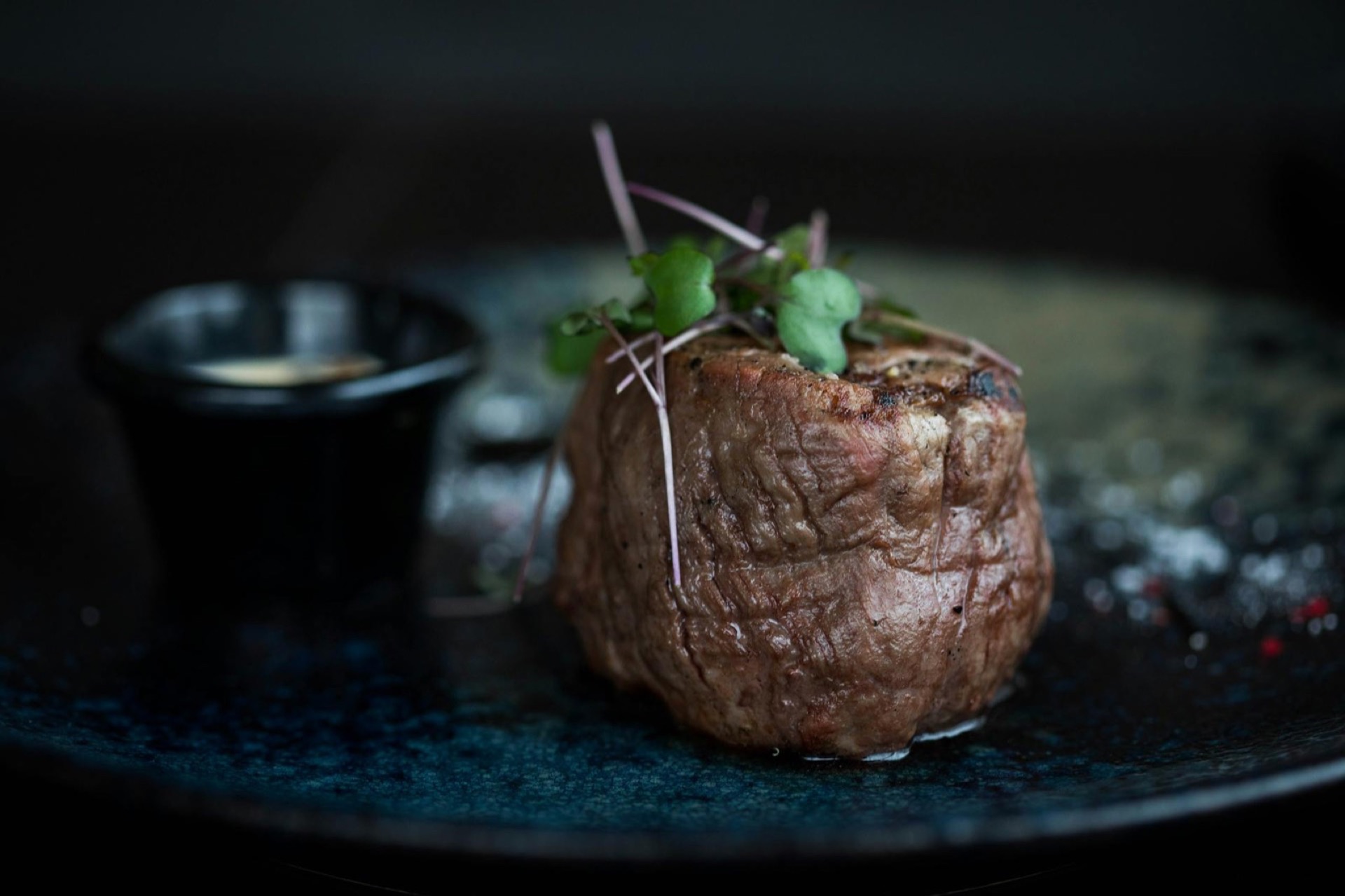Tournedos de bœuf saisi, microgreens en garniture, sur assiette ardoise foncée