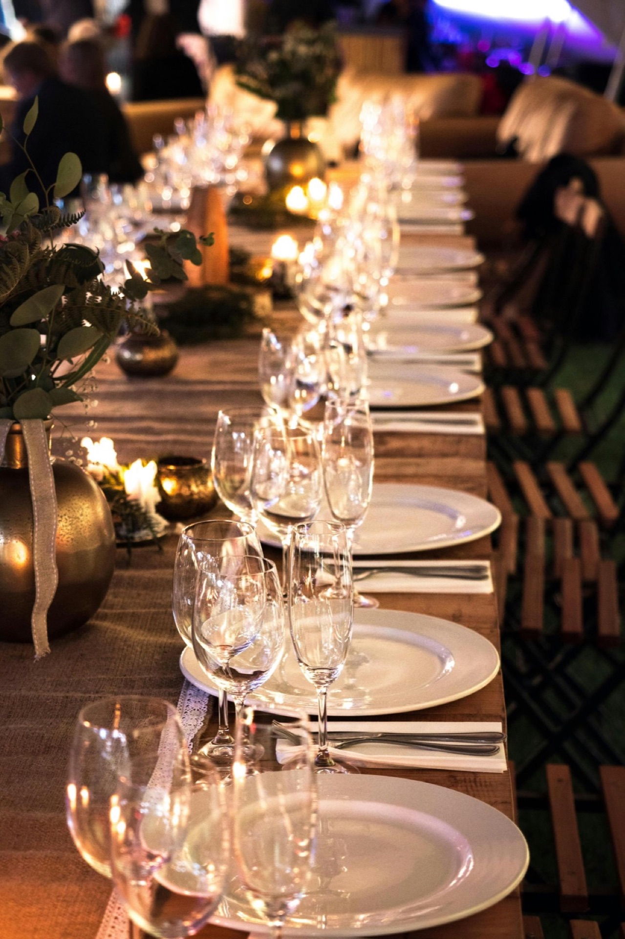 Longue table dressée avec verres, candélabres en laiton et bougies, ambiance soirée intime